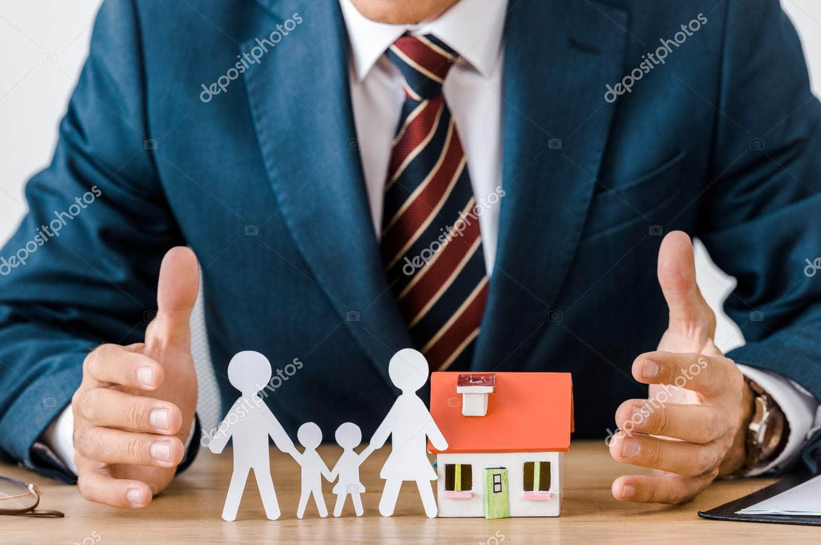 Businessman with paper family and house models for insurance planning.