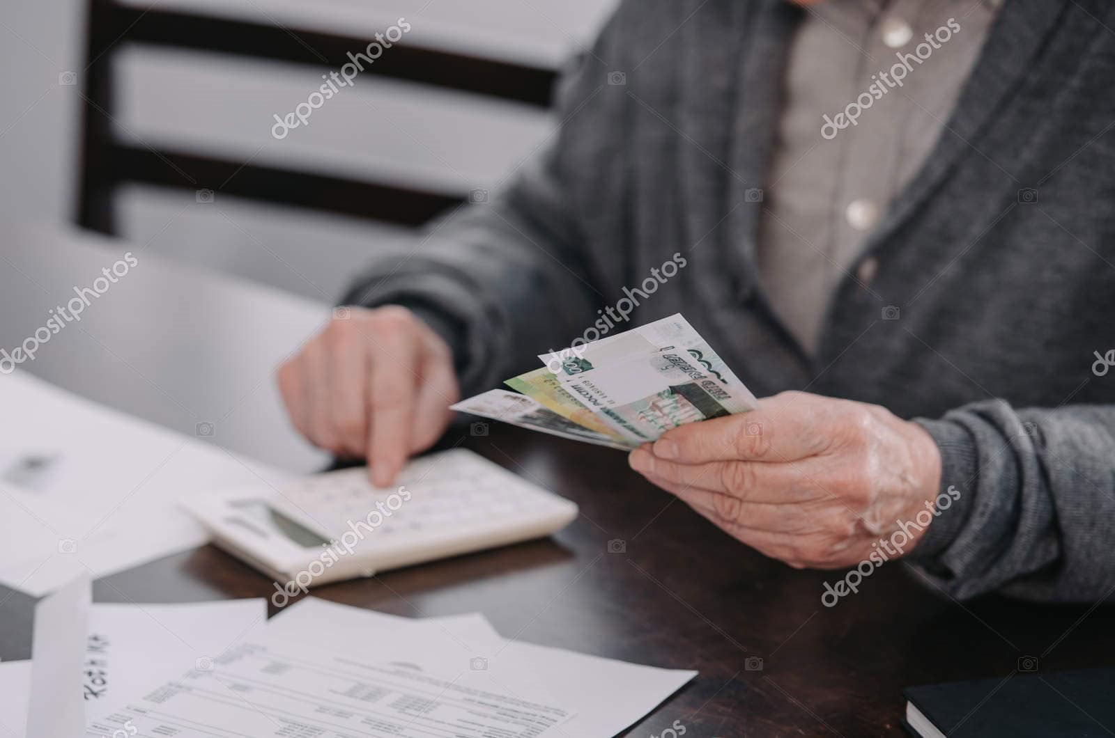 Person reviewing financial documents and cash at desk for retirement planning.