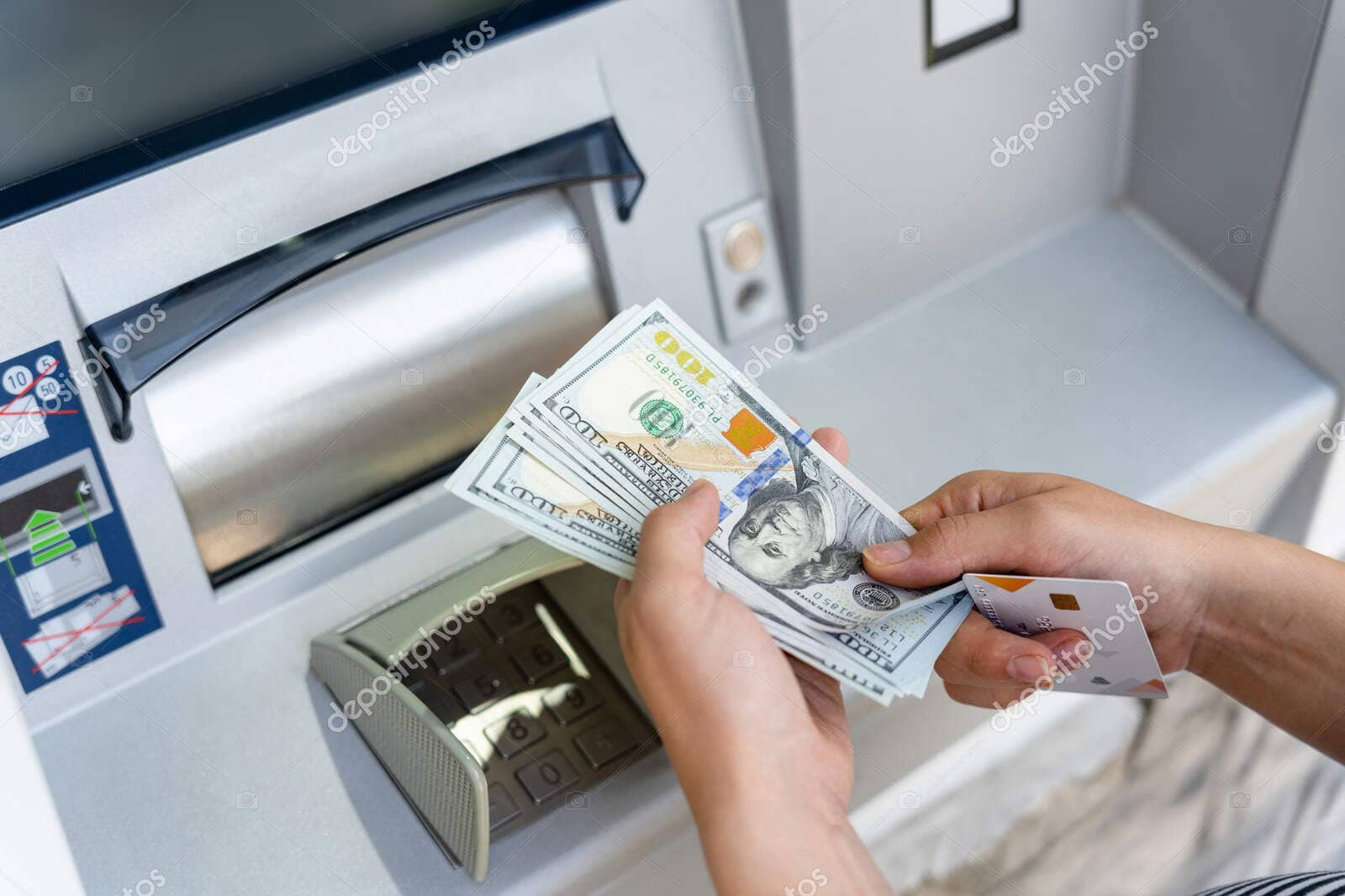 ATM cash withdrawal with hundred-dollar bills.