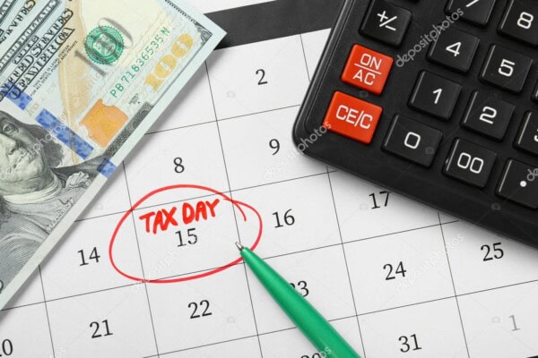 Calendar with tax day marked, calculator, and cash for financial planning.